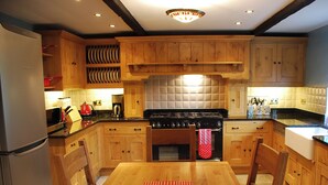 A kitchen with wooden cabinets, a stove, a microwave, and a dining table with chairs. - 2 bedroom accommodation in Youlgreave near Bakewell (Youlgreave near Bakewell)