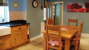 A kitchen with wooden cabinets, a black countertop, and a dining table with chairs. - 2 bedroom accommodation in Youlgreave near Bakewell (Youlgreave near Bakewell)