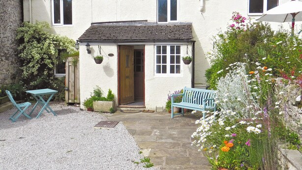 A quaint cottage with a gravel patio, a wooden door, and a blue bench. - 2 bedroom accommodation in Youlgreave near Bakewell (Youlgreave near Bakewell)