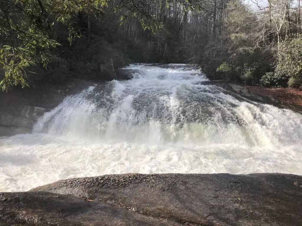 Una cascada deslizándose sobre rocas en un área boscosa.