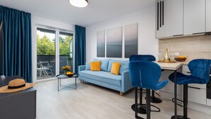 A modern living room with a light blue sofa, two blue chairs, a small coffee table, and a dining area with a white table and blue chairs.