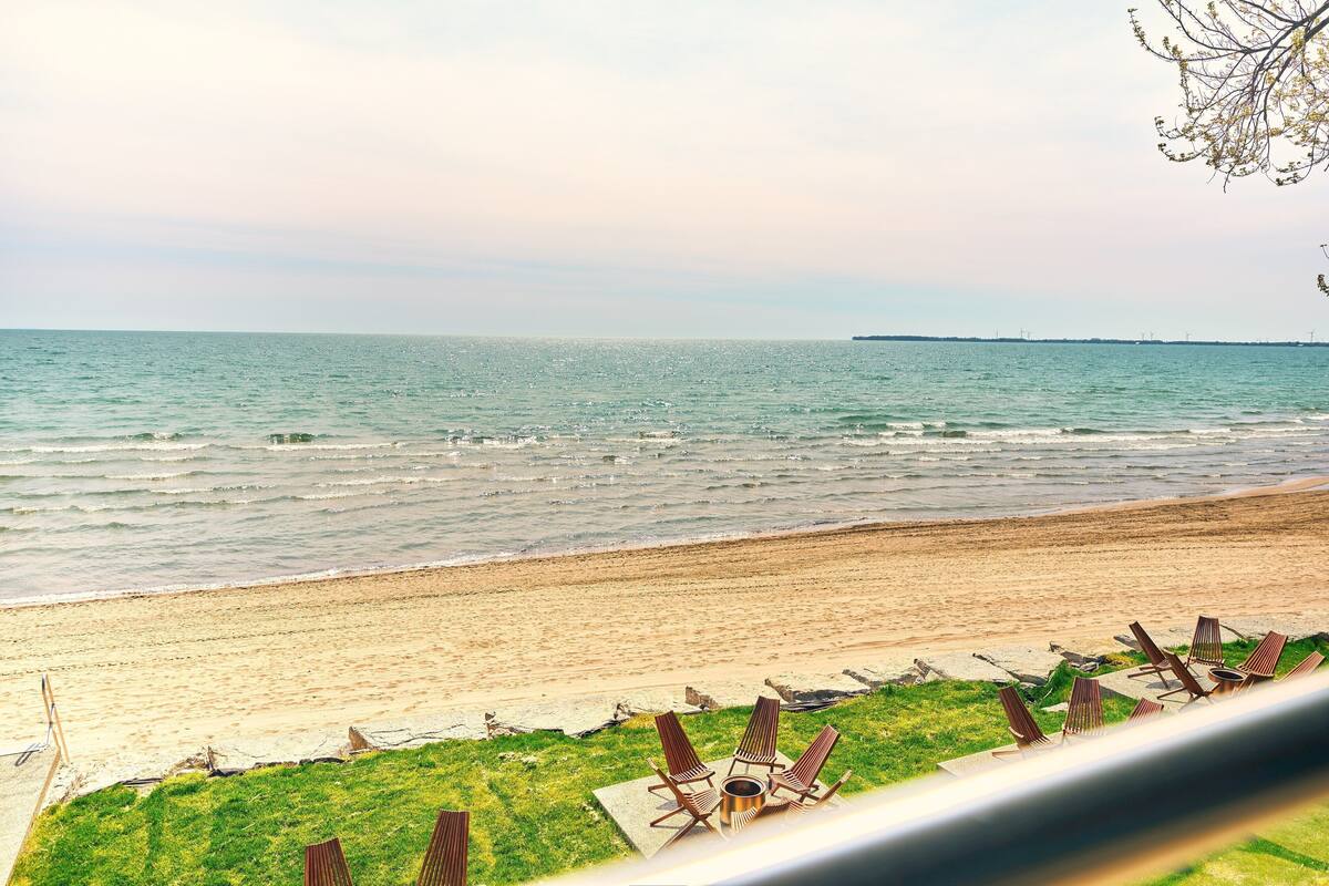 A beach view with lounge chairs and a fire pit.