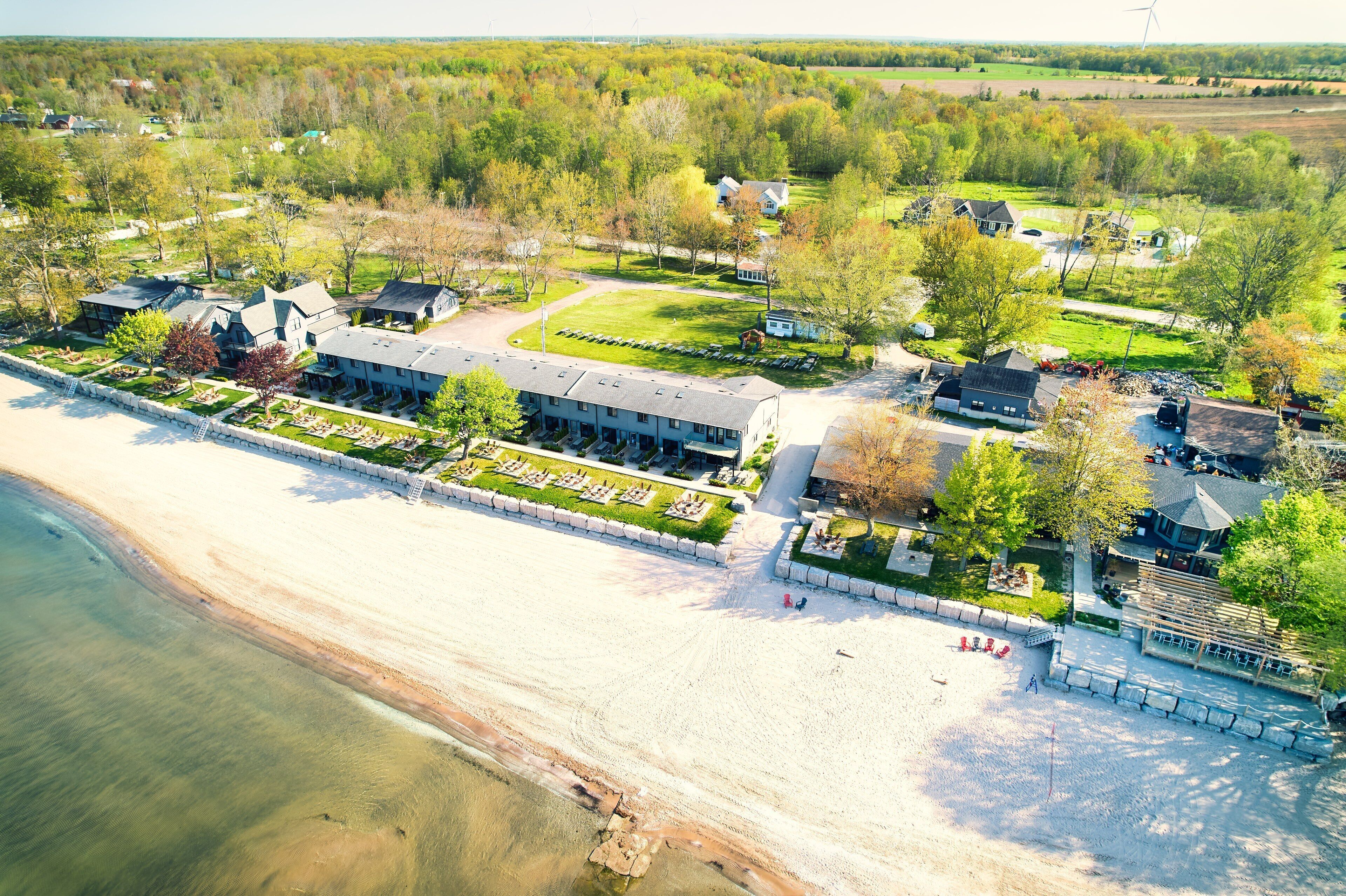 An aerial view of a coastal resort with a beach, multiple buildings, and a golf course.