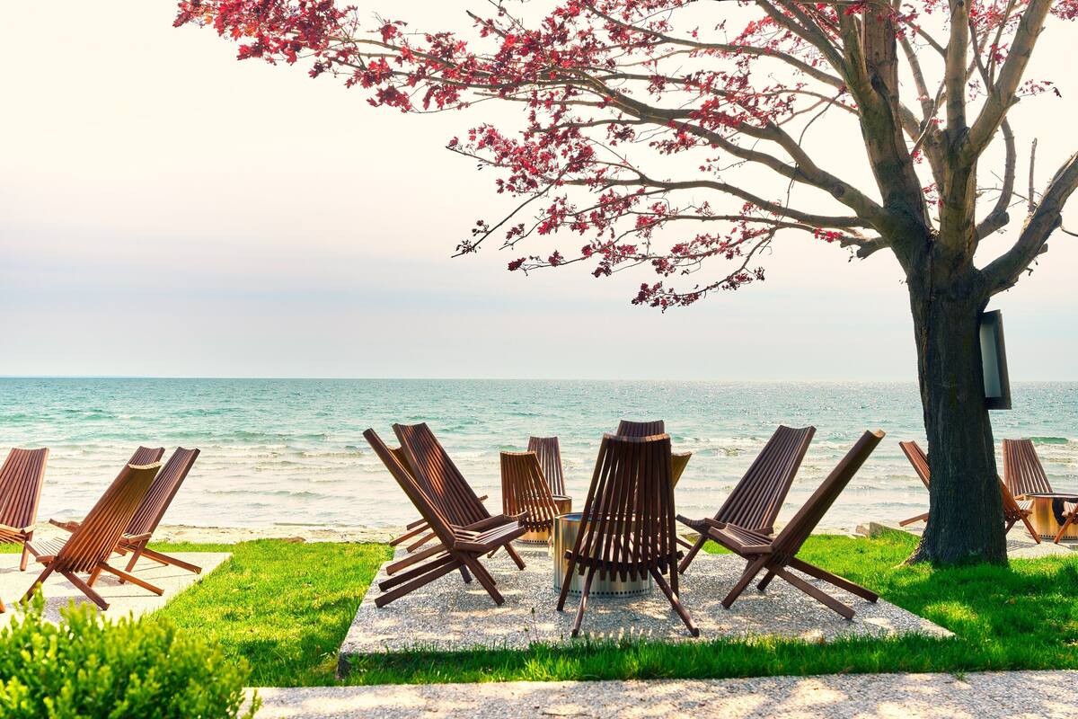 A beachside seating area with wooden chairs and a table, overlooking the ocean.