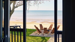 A beach view from a room with a table and chairs on a deck. - Long Beach Resort (Wainfleet)