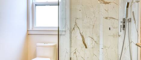 Une salle de bain avec des toilettes, une douche à parois de verre et une fenêtre.
