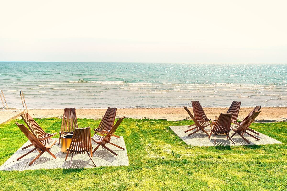 A beachside seating area with wooden loungers and a table, overlooking the ocean.