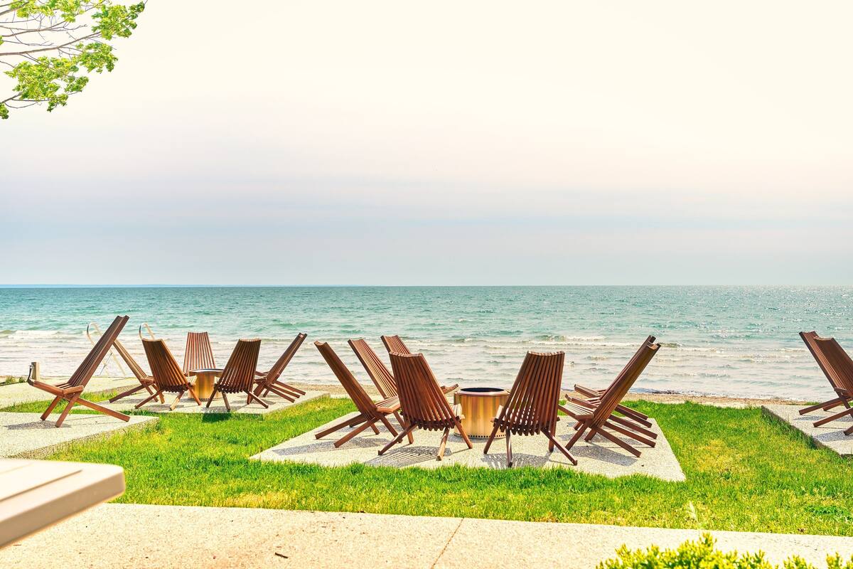 A beachside lounge with lounge chairs and a small table, overlooking the sea.