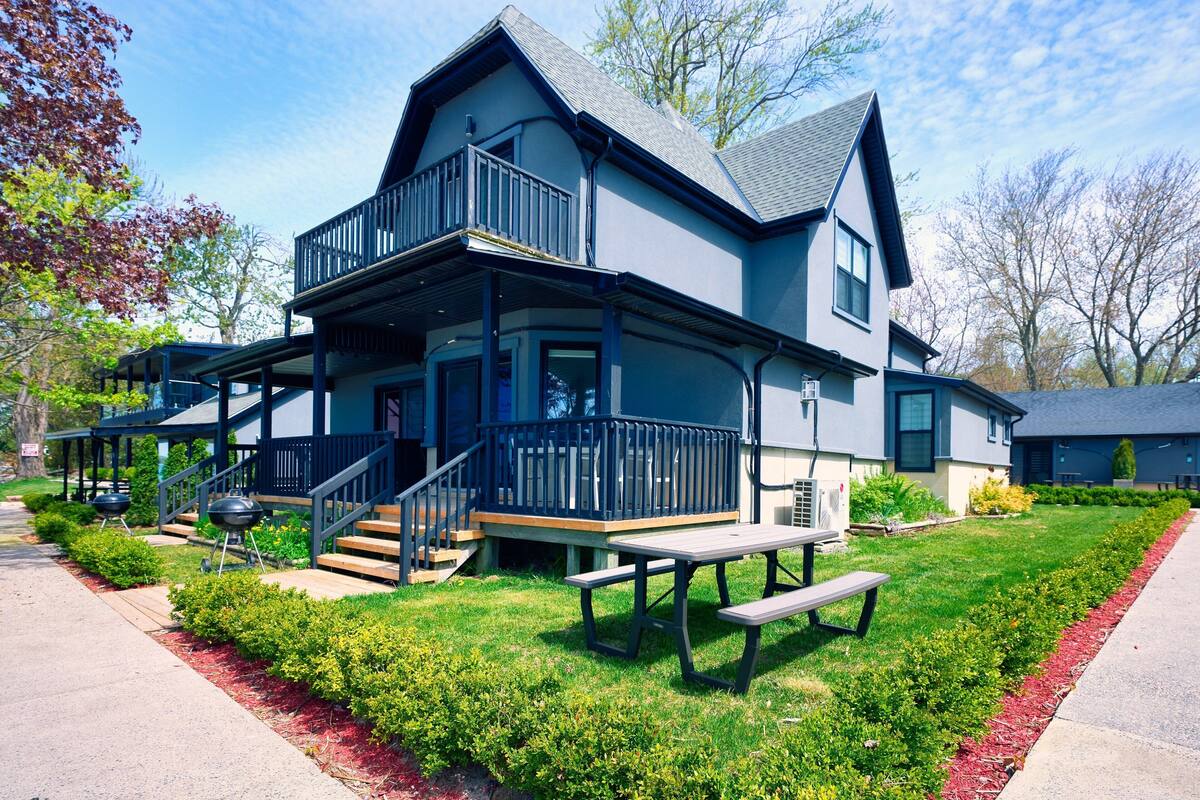 A two-story house with a balcony, a front porch, and a picnic table.