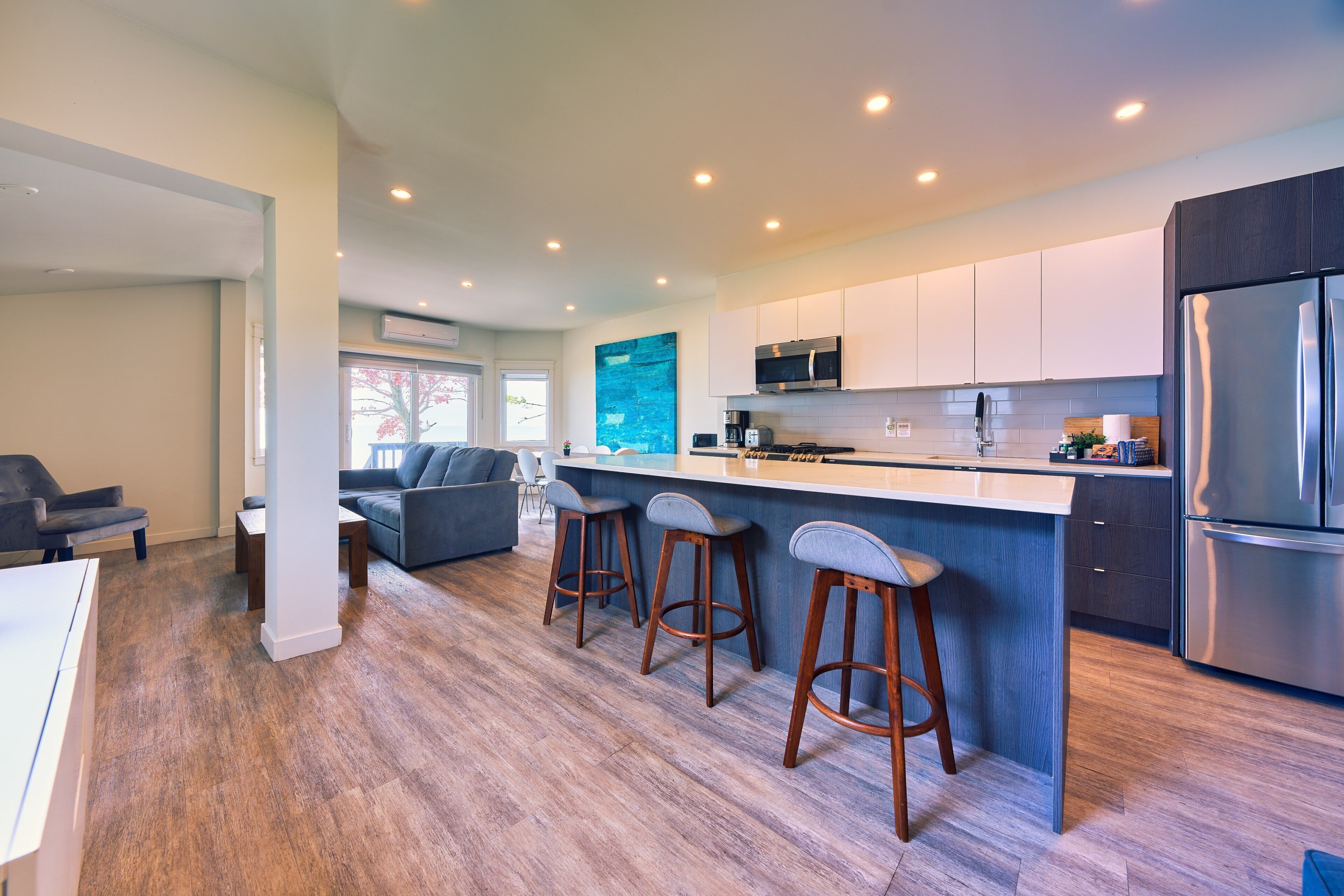 A modern kitchen with a central island, bar stools, and a built-in oven.