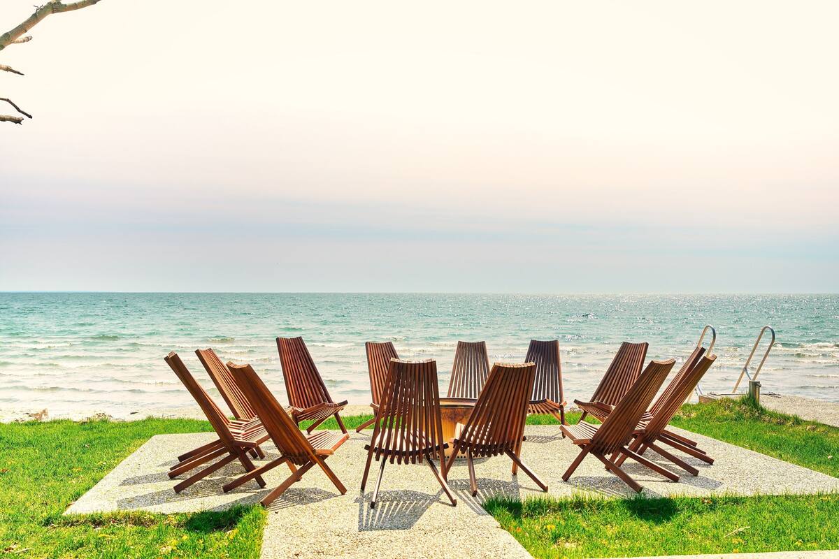 A beachside seating area with wooden chairs and a table, overlooking the sea.