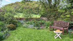 A garden with a wooden bench and a table with fruits and vegetables. - 1 bedroom accommodation in Baslow (Baslow)