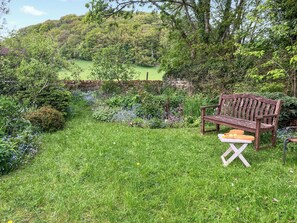 A garden with a wooden bench and a table with fruits and vegetables.