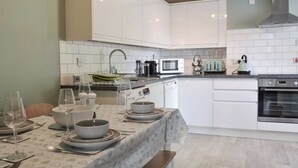 Cuina moderna amb armaris blancs, microones, tetera i rentavaixelles.