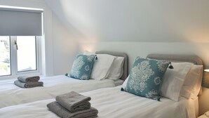 Una habitació d'hotel amb dos llits, cada un amb un coixí blanc i amb dibuixos, i una finestra amb vistes.