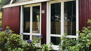 A house with a dark grey roof, white window frames, and red siding.