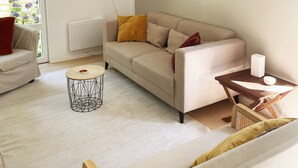 A modern living room with a beige sofa, a coffee table, and a wooden ceiling.