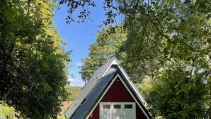 A red barn with a sloped roof, surrounded by lush green trees and a well-maintained lawn.