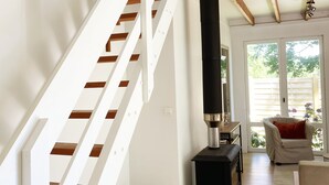 A spacious living area with a wooden staircase, a fireplace, and a view of the outdoors.