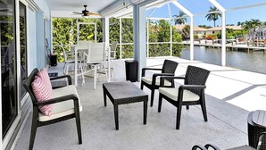 Eine überdachte Außenveranda mit Sitzgelegenheiten, Deckenventilatoren und Blick auf das Wasser.