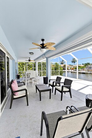 A covered outdoor patio with seating, ceiling fans, and a view of the water.