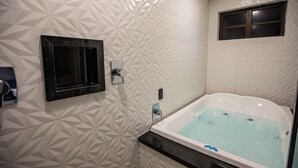 A modern bathroom with a freestanding bathtub, geometric patterned tiles, a small window, and a towel rack. - Drops Motel Campinas (Campinas)