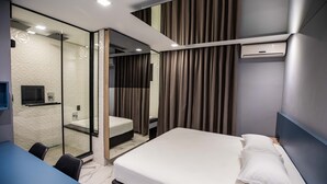 A modern hotel room with a bed, a desk, a mirror, and a shower area. - Drops Motel Campinas (Campinas)