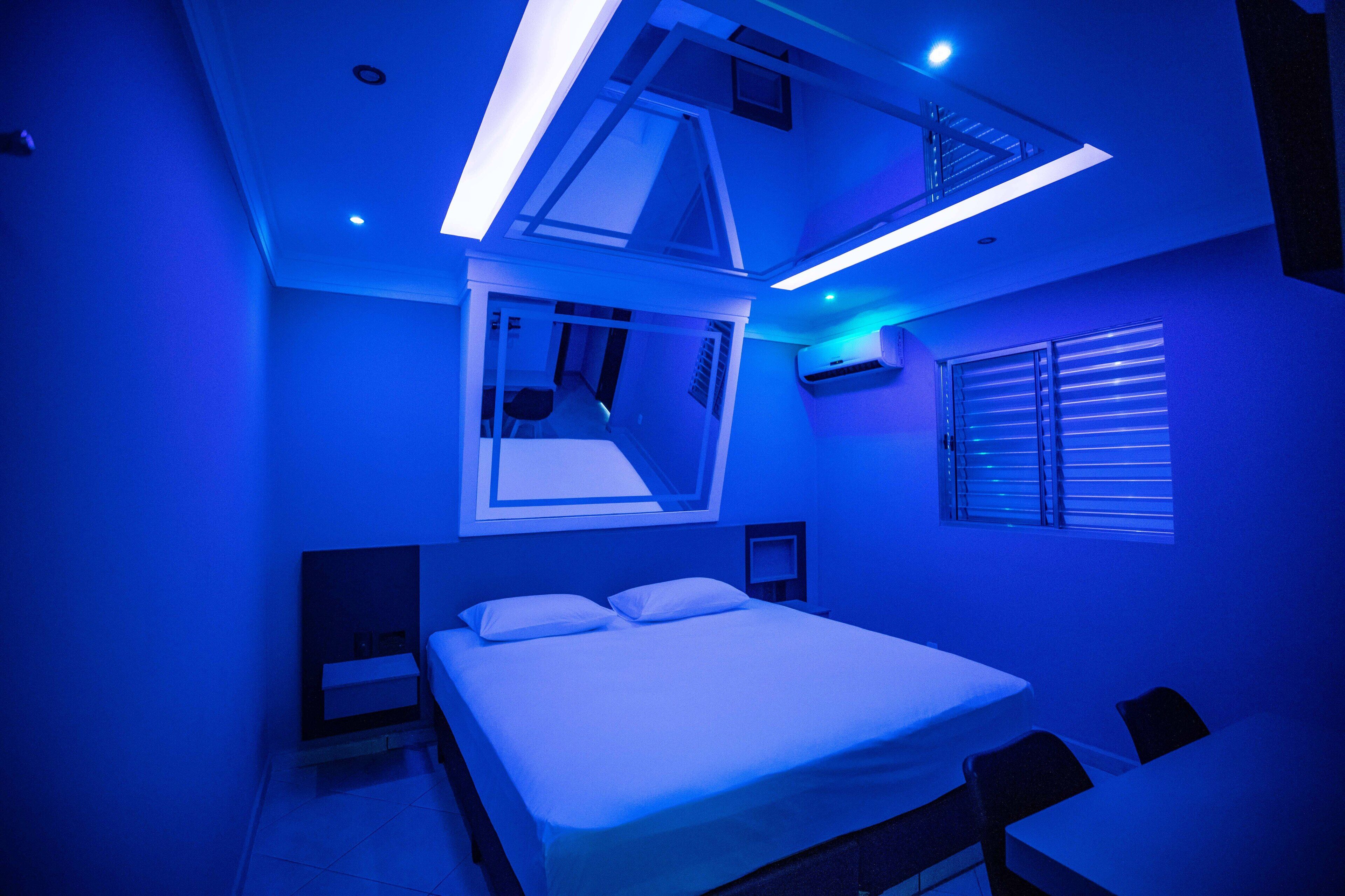 Quarto moderno com claraboia, cama, escrivaninha e janela com persianas.