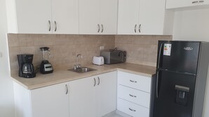 A modern kitchen with white cabinets, a black refrigerator, a coffee maker, a toaster, and a blender. - St. penthouse w/jacuzzi (Sosúa)