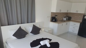 A hotel room with a bed, a small bedside table, a kitchen area with a coffee maker, toaster, and refrigerator. - St. penthouse w/jacuzzi (Sosúa)