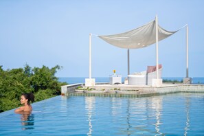 A pool with a canopy and lounge chairs, surrounded by greenery and a clear view of the sea. - Baan Bon Khao - Choeng Mon (Koh Samui)