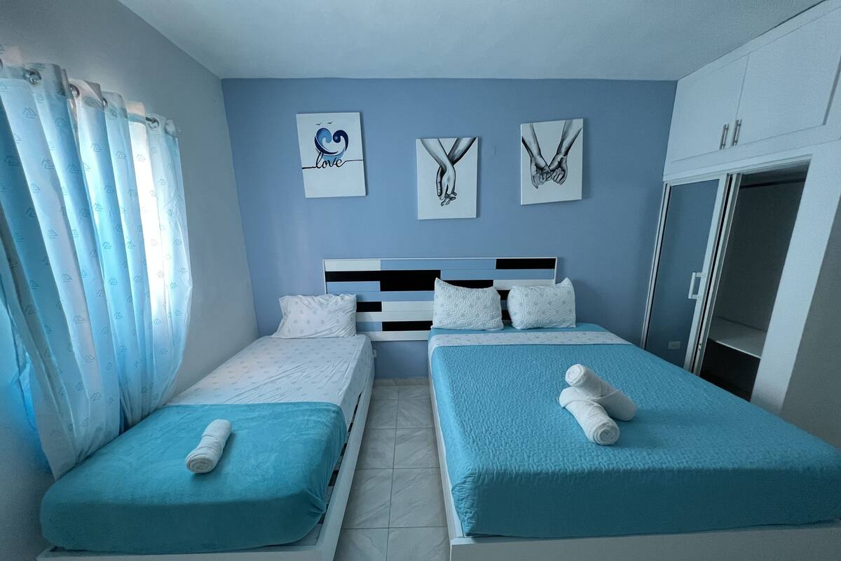 A twin room with two beds, a wardrobe, and artwork on the wall.
