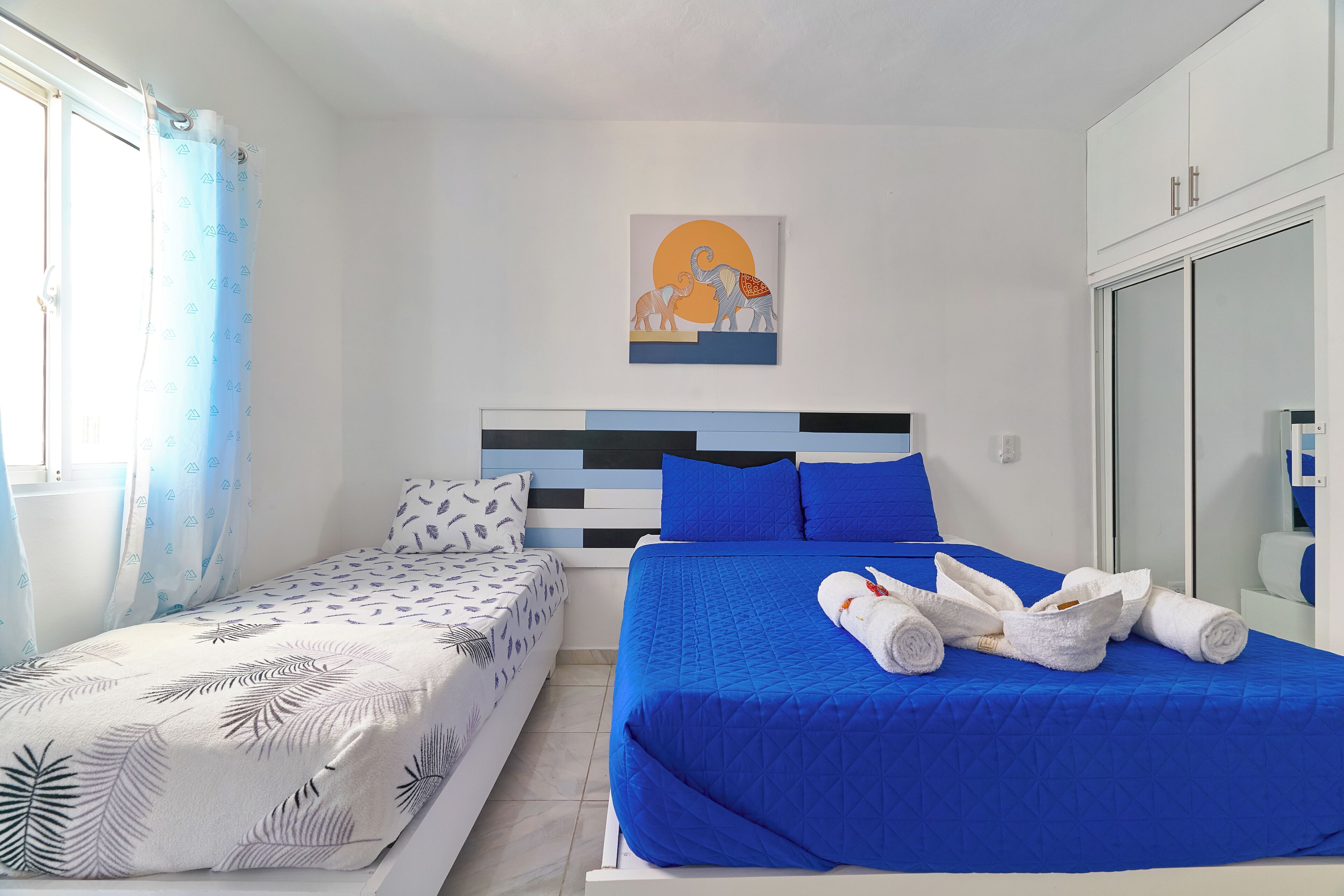Un dormitorio con una cama, una cama adicional, un cuadro y un armario.