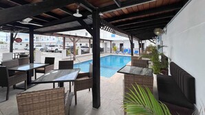 Un espace piscine extérieur agrémenté de meubles en osier et d’un coin salon abrité.