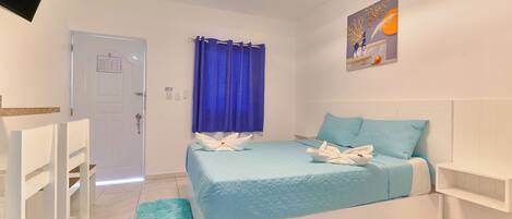 Quarto com cama, cortina azul, pintura e porta branca.