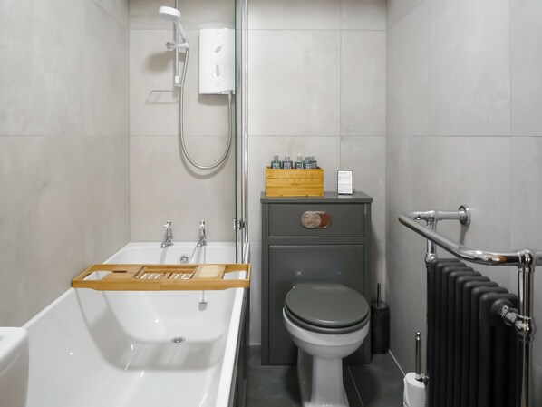 A modern bathroom with a bathtub, toilet, and a shower area. - 1 bedroom accommodation in Stainforth near Settle (Stainforth near Settle)