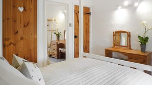 A bedroom with a bed, wooden wardrobe, a mirror, and a desk with a plant. - 1 bedroom accommodation in Stainforth near Settle (Stainforth near Settle)