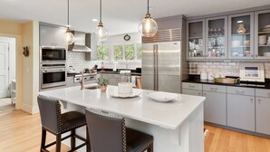 A modern kitchen with a central island, stainless steel appliances, and pendant lighting. - Private Pool, Elevator, 4-Seater Golf Cart (fee), Golf Course view- 8 Hidden Green (Isle Of Palms)