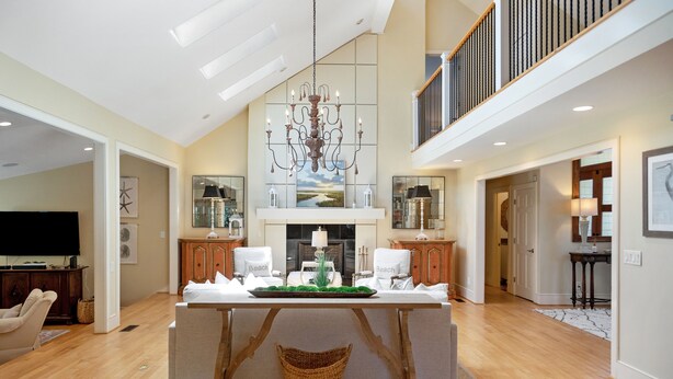 A spacious living area with a high ceiling, a chandelier, a central island with a green centerpiece, and a large window with a view. - Private Pool, Elevator, 4-Seater Golf Cart (fee), Golf Course view- 8 Hidden Green (Isle Of Palms)