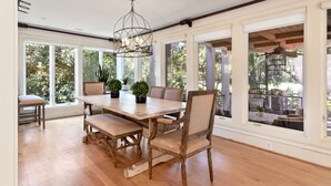 A dining area with a wooden table, cushioned chairs, and potted plants. - Private Pool, Elevator, 4-Seater Golf Cart (fee), Golf Course view- 8 Hidden Green (Isle Of Palms)