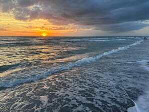 A beach with waves and a sunset.
