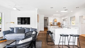 Una cocina moderna con armarios blancos, una isla central y taburetes de bar.