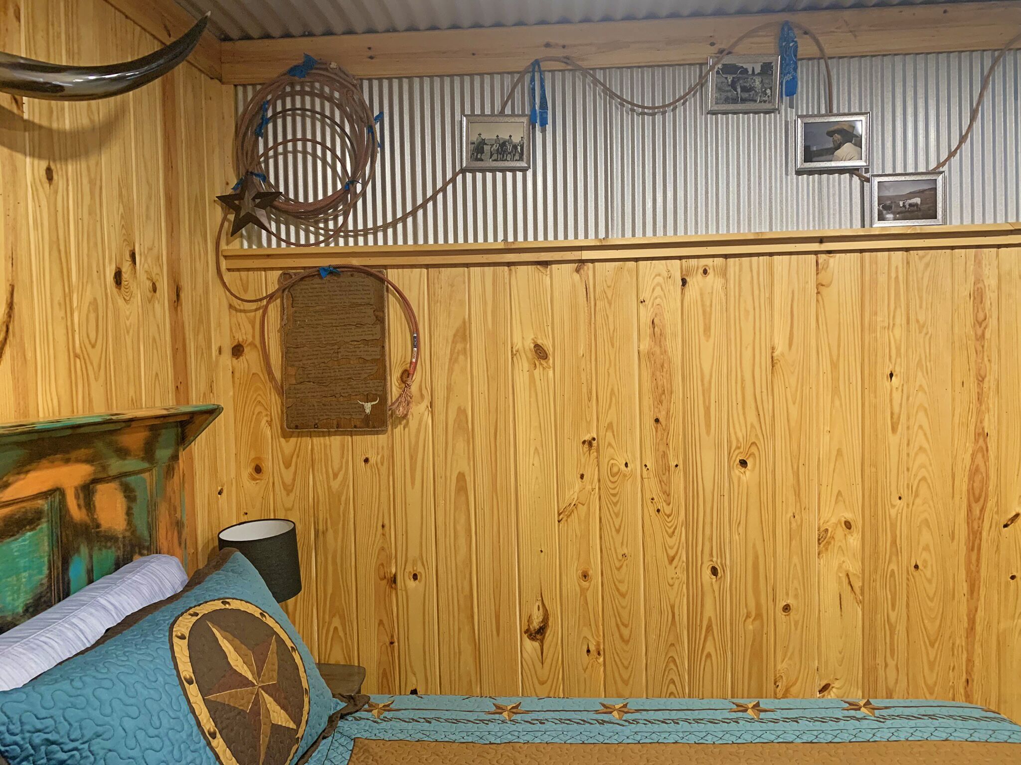 A rustic wooden room with a bed, a wall-mounted shelf with framed pictures, and a decorative star.