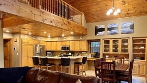 A spacious kitchen with wooden cabinets, a central island, and a dining area with wooden chairs and a table. - Dog friendly, lakefront home perfect for families (Eagle River)