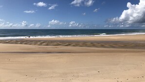Een strand met een heldere lucht en golven.