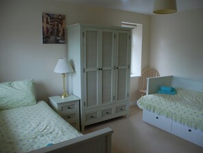 A bedroom with a bed, a nightstand, a lamp, a wardrobe, and a chair.