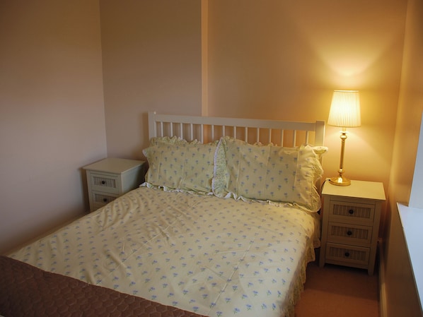 Une chambre à coucher comprenant un lit, une lampe de chevet, une table de chevet et une commode.