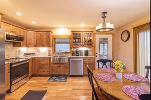 Enjoy cooking in this well-equipped kitchen with a refrigerator, oven, and microwave, and dining area with a wooden table and chairs.