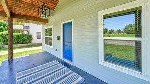 Eine geschlossene Veranda mit einer blauen Tür, einem Fenster mit Jalousien und einem Streifen Teppich.