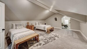 Ein geräumiges Schlafzimmer im Dachgeschoss mit zwei Betten, einer hölzernen Bank und einem großen Teppich.